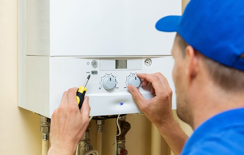 Heating Engineer Adjusting A Boiler