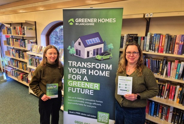Two colleagues standing together with a roller banner promoting Green Homes in Lancashire